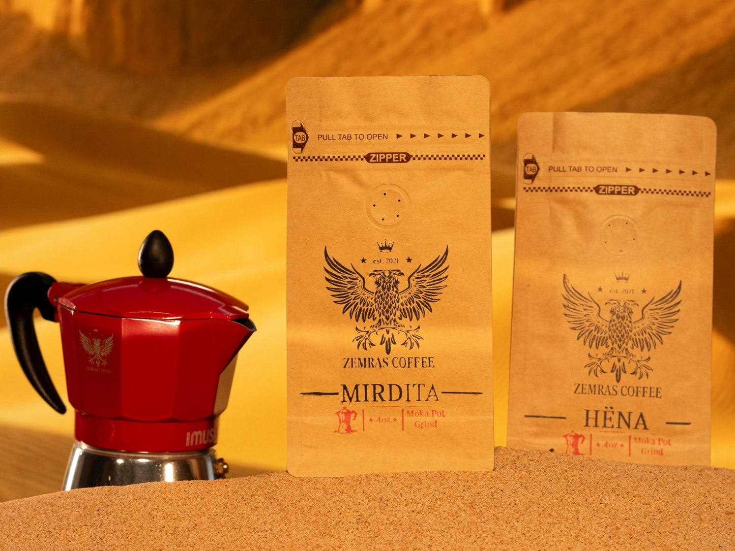 Specialty Moka pot duo featuring Mirdita and Hëna coffee bags on a traditional sand-brewing station, roasted by Enderly Coffee.