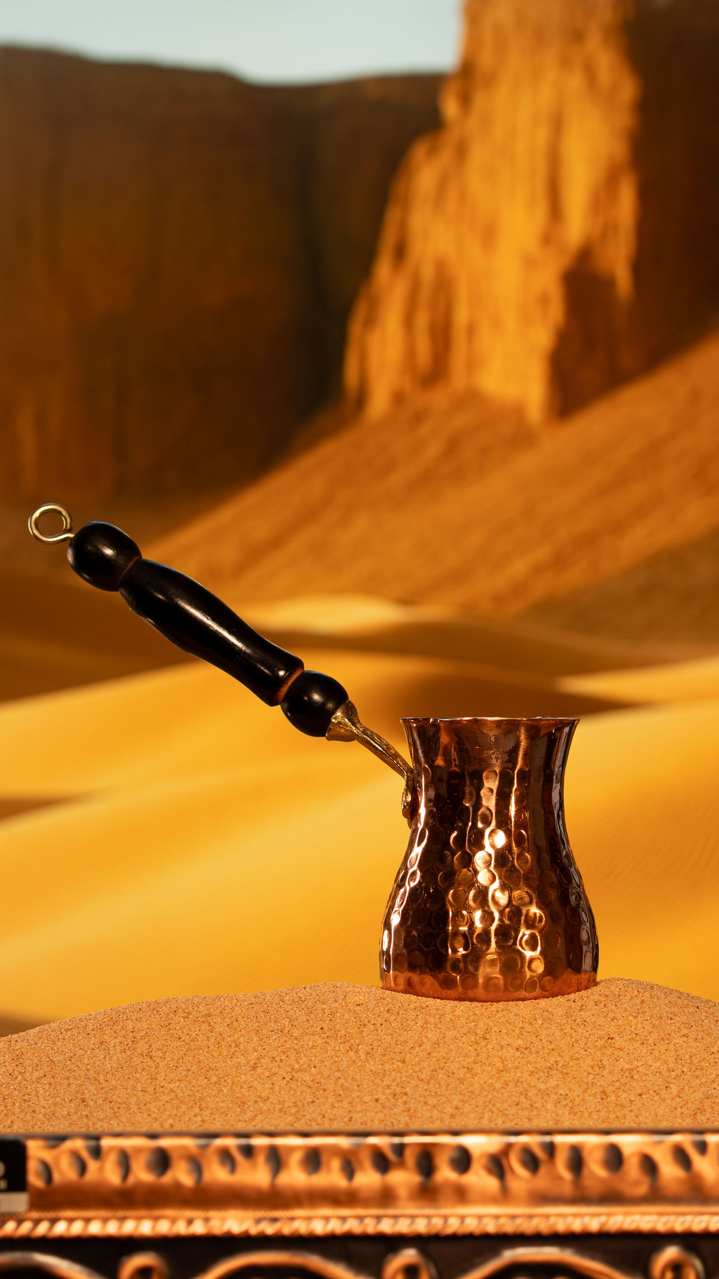 Vertical profile of a traditional handcrafted xhezve showing the hammered copper finish and wooden handle.