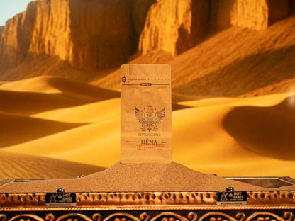 Hëna "Moon" organic Honduran decaf coffee bag on sand, roasted medium-dark for a smooth, chocolaty taste.